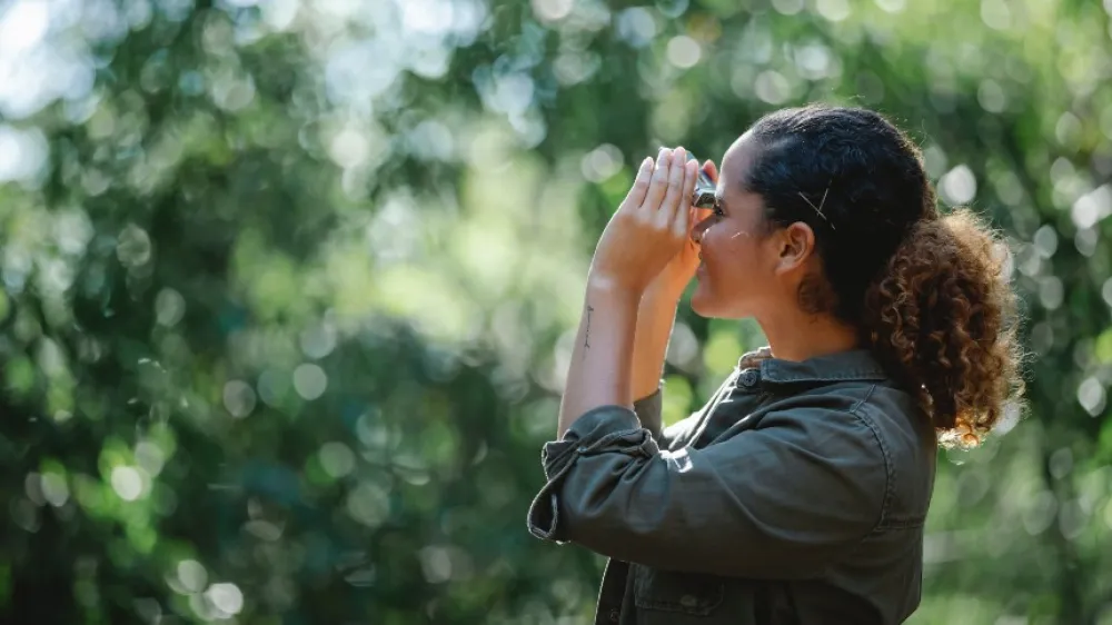 Ethnic woman looking at binoculars 860x484