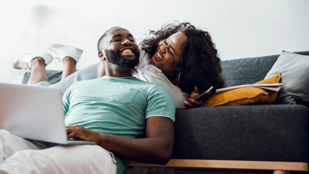 Hero Happy young Black male and female smiling to each other while spending time at home