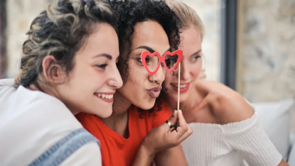 Three women posing for a photo with heart shaped prop 860x484