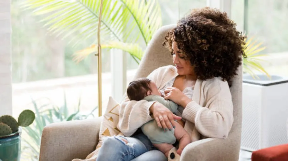 Woman sitting in a comfy chair breastfeeding her baby